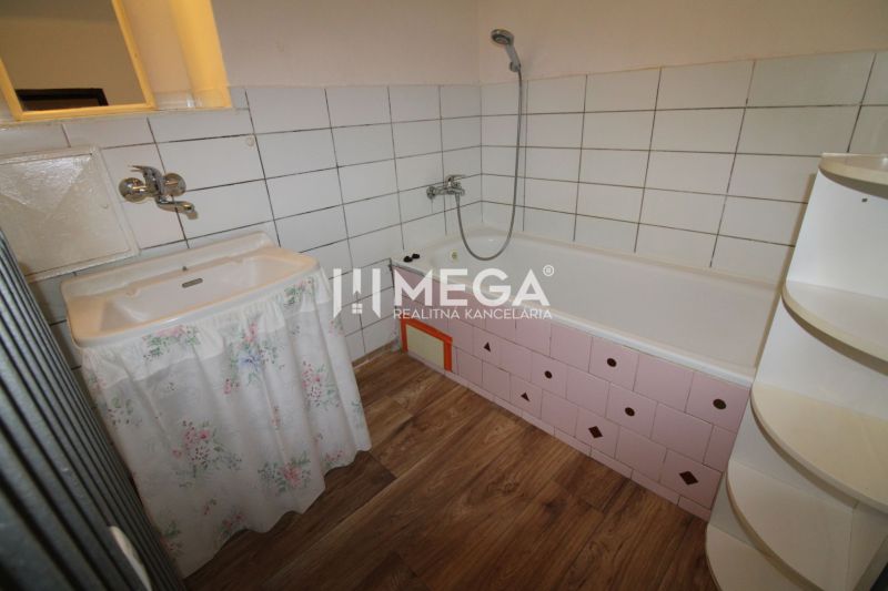 Badezimmer in einer 2-Zimmer-Wohnung mit Badewanne, Waschbecken und Boden mit Holzdekor.