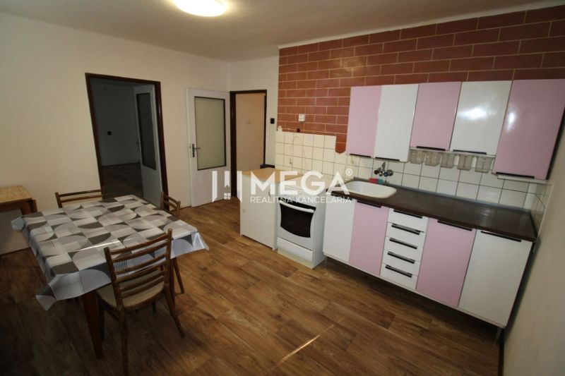Küche in einer 2-Zimmer-Wohnung mit Holzboden, Esstisch und Schränken.