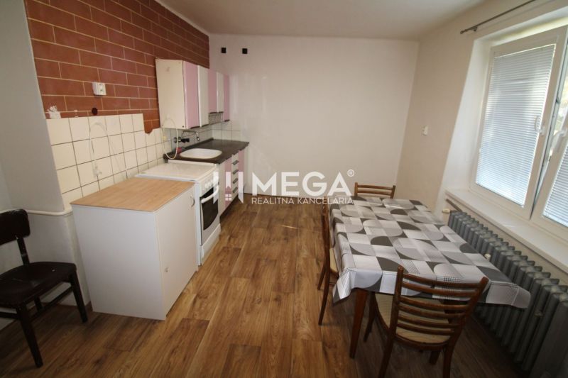 Küche in einer 2-Zimmer-Wohnung mit Holzboden, Esstisch und Kochbereich.