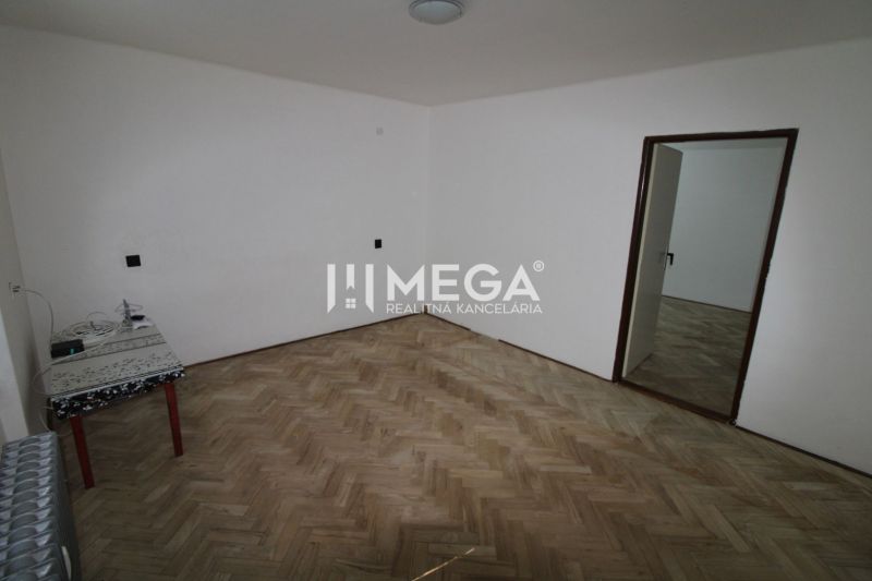 Ein Zimmer in einer 2-Zimmer-Wohnung mit einem Boden in Holzoptik und einem Tisch in der Ecke.