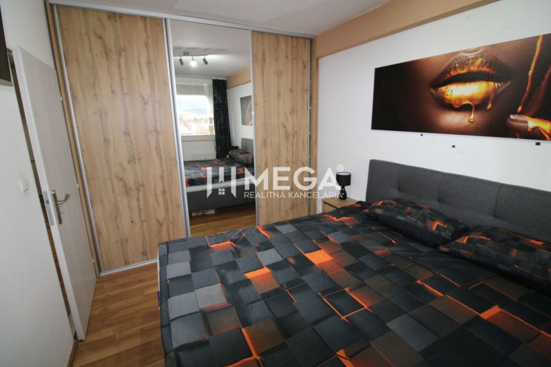 Schlafzimmer mit Bett und Schrank mit Schiebetüren, Boden mit Holzdekor.