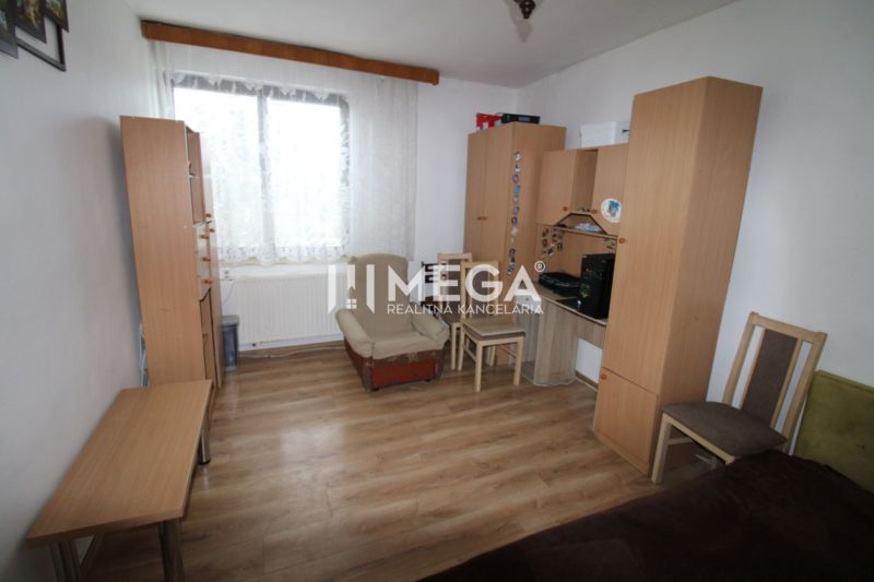 Ein Zimmer mit Holzelementen, Möbeln, einem Sessel und einem Tisch in einem Einfamilienhaus.