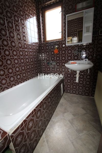 Ein Badezimmer in einem Einfamilienhaus mit braunen Fliesen und einer Badewanne.