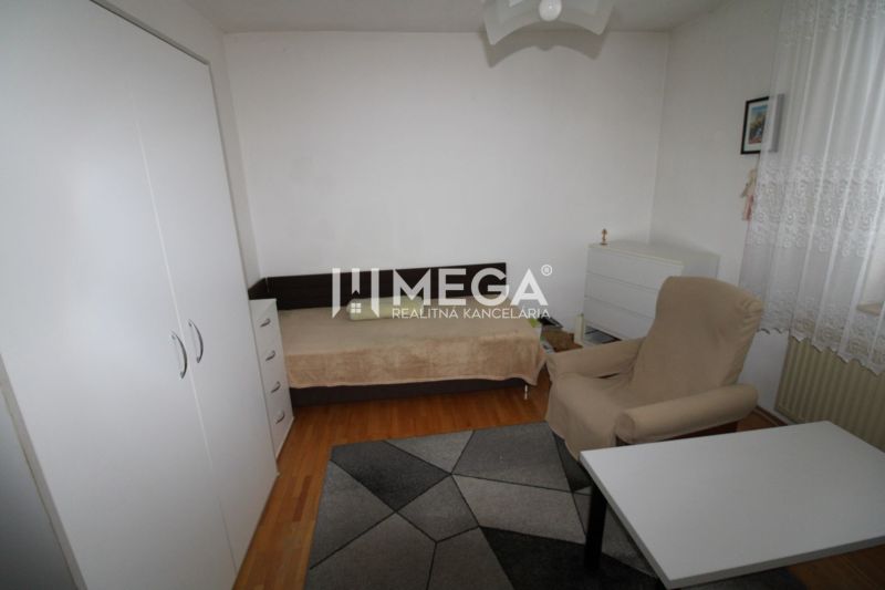 Ein Zimmer in einem Einfamilienhaus mit einem Bett, einem Sessel, einem Tisch und einem Boden mit Holzdekor.