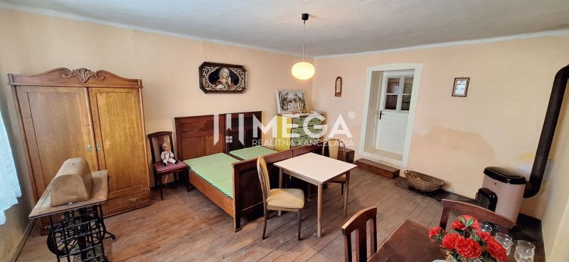 Ein Zimmer in einem Einfamilienhaus mit einem Bett, Möbeln und einem Boden mit Holzdekor.