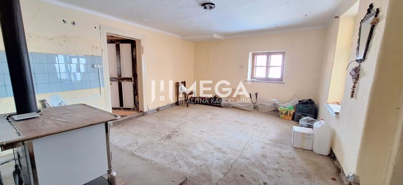 Ein Zimmer in einem Einfamilienhaus mit einem einfachen Küchenofen und einem Betonboden.