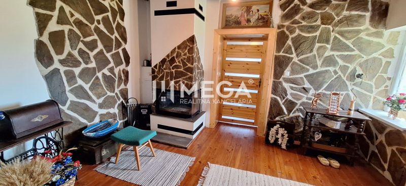 Ein Zimmer in einem Einfamilienhaus mit Kamin, Steinwänden und einem Boden in Holzoptik.
