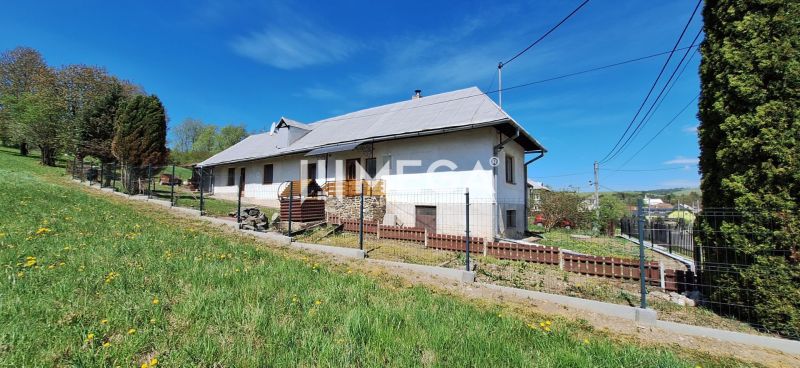 Ein Einfamilienhaus in der Gemeinde Zbudská Belá, umgeben von grünen Rasenflächen und Bäumen.