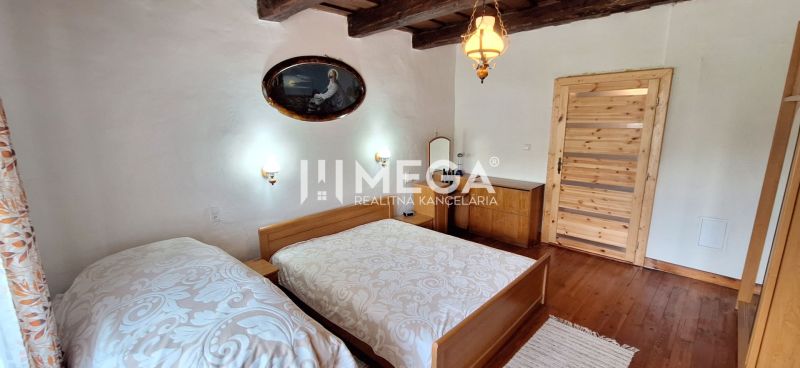 Schlafzimmer mit zwei Betten, Holzbalkendecke und Holzboden in einem Einfamilienhaus.