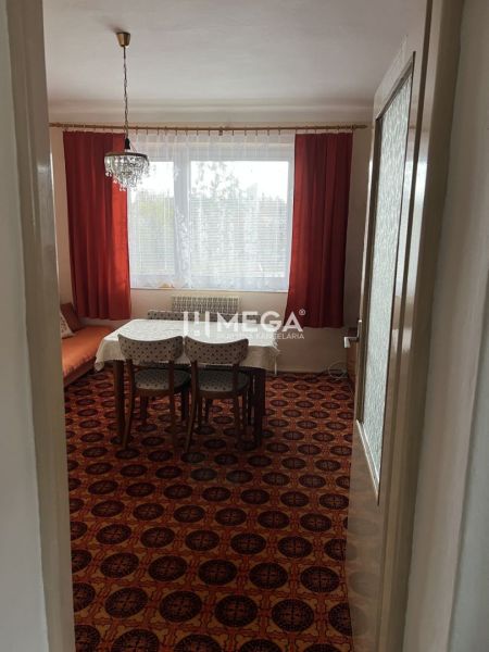 Innenraum eines Einfamilienhauses mit einem Teppich in rotem Dekor, Esstisch und Kronleuchter.