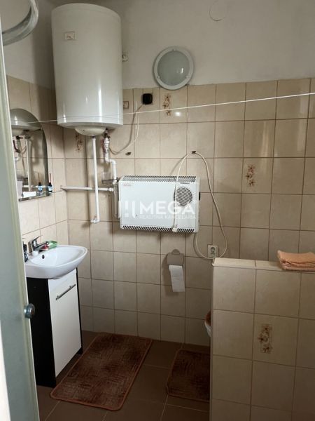 Badezimmer mit Gasheizung und Waschbecken im Einfamilienhaus, Fliesenboden, einfache Ausstattung.