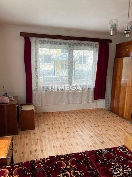 Ein Zimmer in einem Einfamilienhaus mit einem Boden in Holzoptik, roten Vorhängen und Schränken.