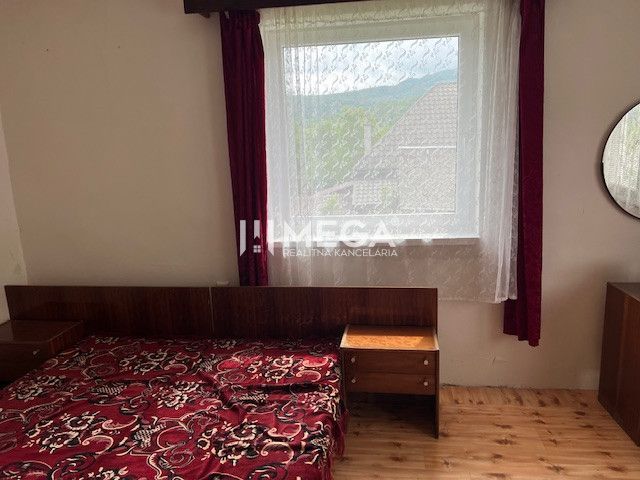 Schlafzimmer in einem Einfamilienhaus mit Bett, Fenster, roten Vorhängen und Holzboden.
