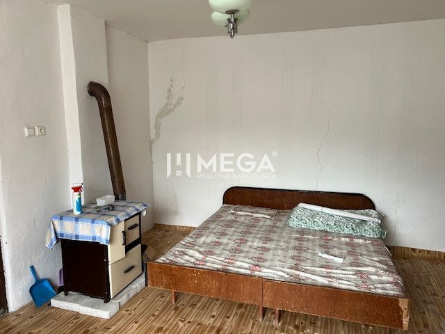 Ein Zimmer in einem Einfamilienhaus mit einem Bett und einem Boden in Holzoptik.