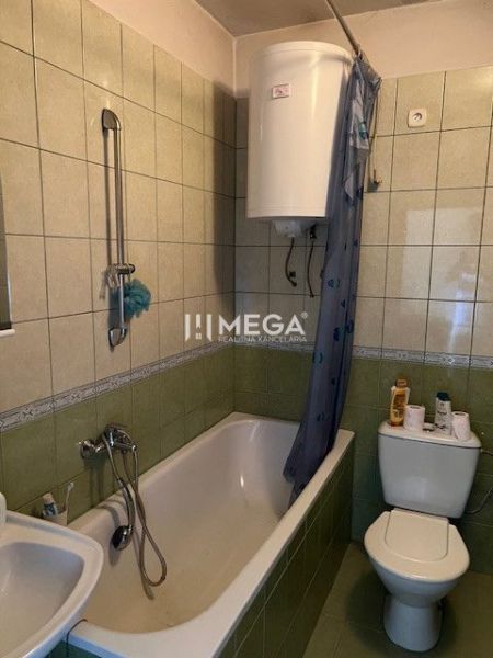 Badezimmer mit Badewanne und Toilette, gefliest mit grünen Fliesen in einem Einfamilienhaus.