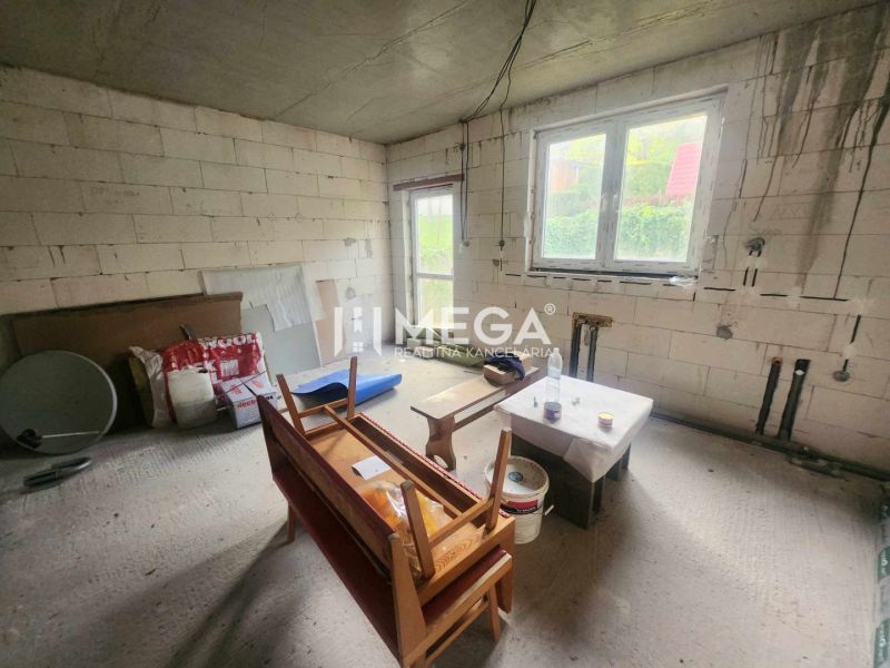 Interieur eines Einfamilienhauses mit rohen Bauwänden, einem Fenster und provisorischen Sitzgelegenheiten.