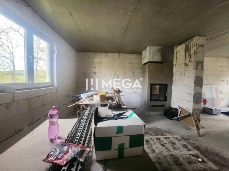 Innenraum eines Einfamilienhauses mit unvollendeten Wänden, Kamin und Baumaterial.