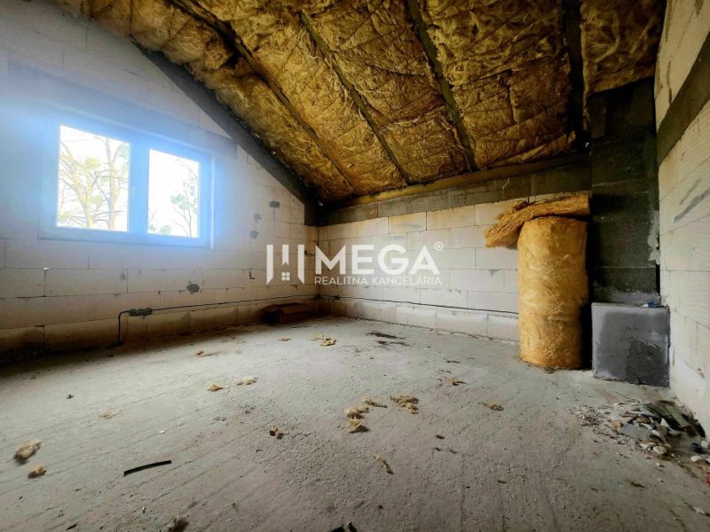 Innenraum eines Einfamilienhauses mit einem unfertigen Zimmer und Dämmmaterial auf dem Boden.