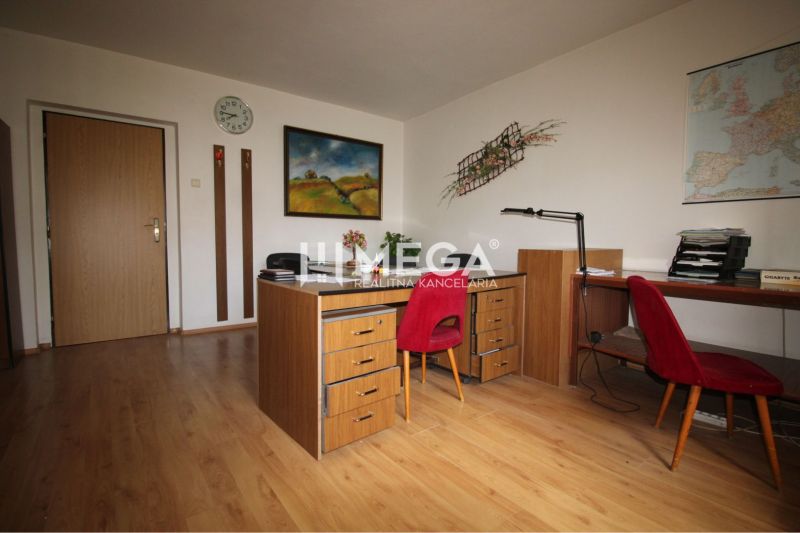 Ein Büro mit einem Boden in Holzoptik, Stühlen und Bildern an den Wänden.