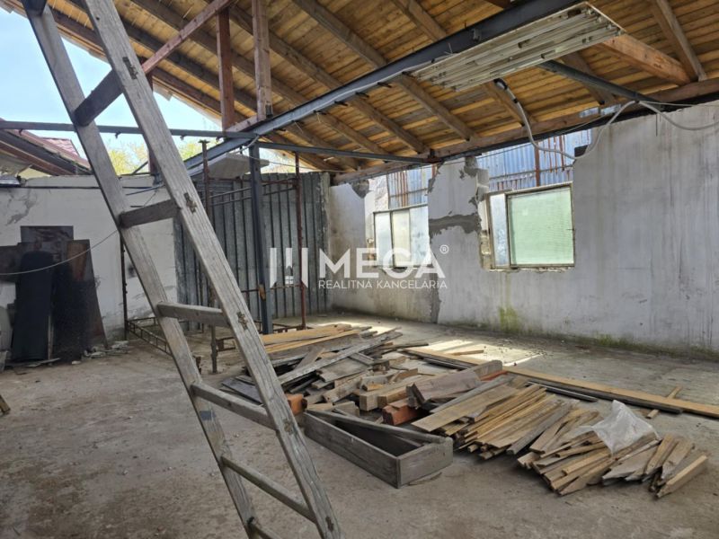 Innenraum eines Einfamilienhauses mit unfertigem Dach, Leiter und einem Haufen Holz auf dem Boden.