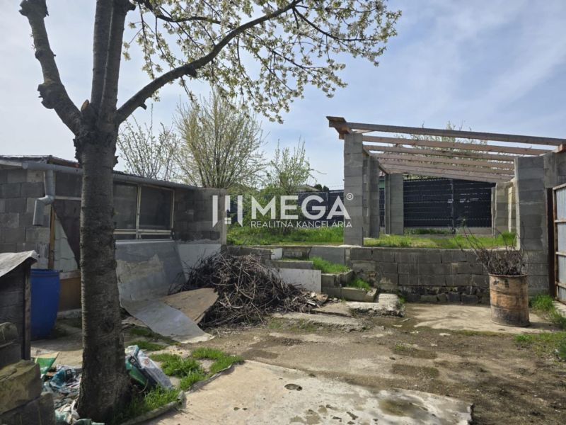 Der Hof eines Einfamilienhauses in Sokoľany mit einem Baum, Baumaterial und einem unvollendeten Bau.