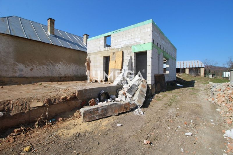 Ein Einfamilienhaus in Zbojná während des Baus mit unvollendeten Mauern und Baumaterialien.