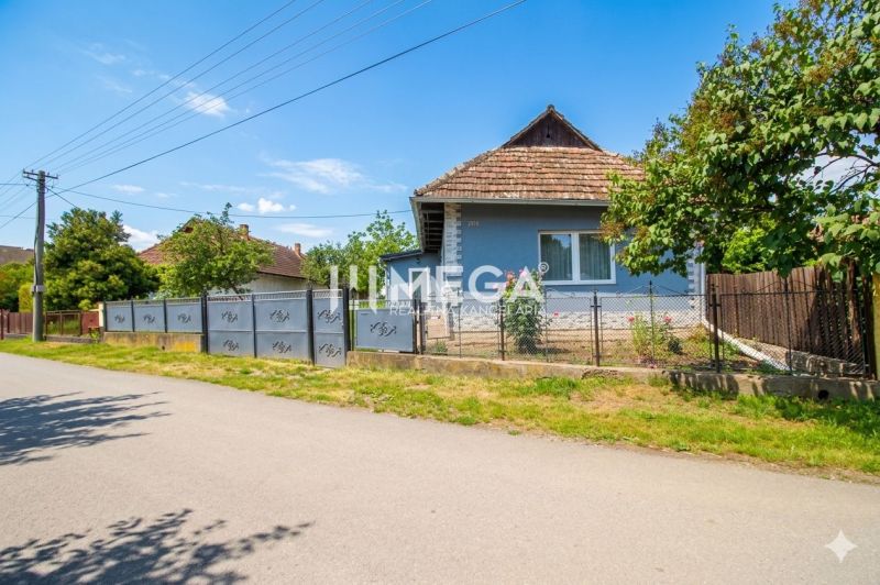 Ein Einfamilienhaus in Veľká Ida mit blauer Fassade und Garten, umgeben von einem Zaun.
