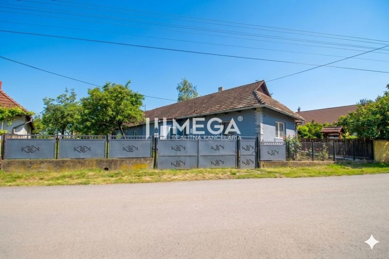 Ein Einfamilienhaus in Veľká Ida mit einem großen Tor und Garten in einer ruhigen Straße.