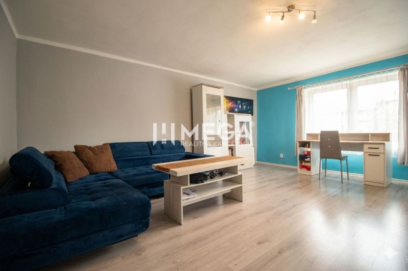 Wohnzimmer mit blauem Sofa, Tisch und Holzboden in einem Einfamilienhaus.