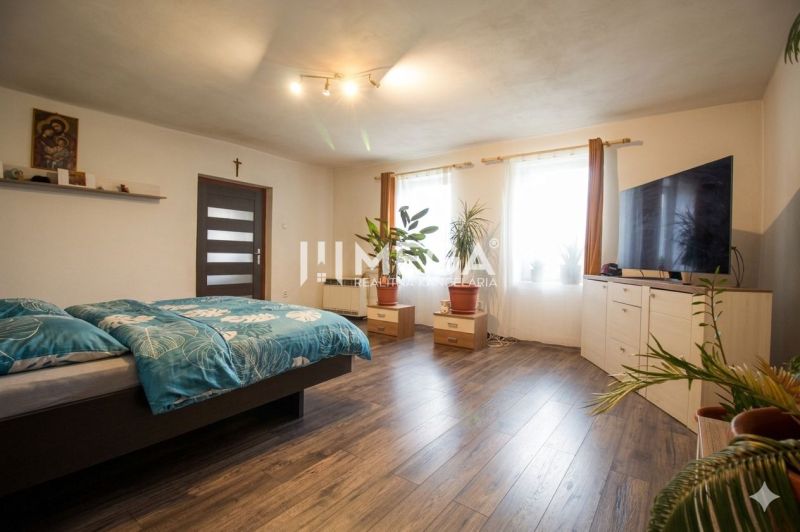 Schlafzimmer in einem Einfamilienhaus mit Holzboden, Bett, Pflanzen und Fernseher.