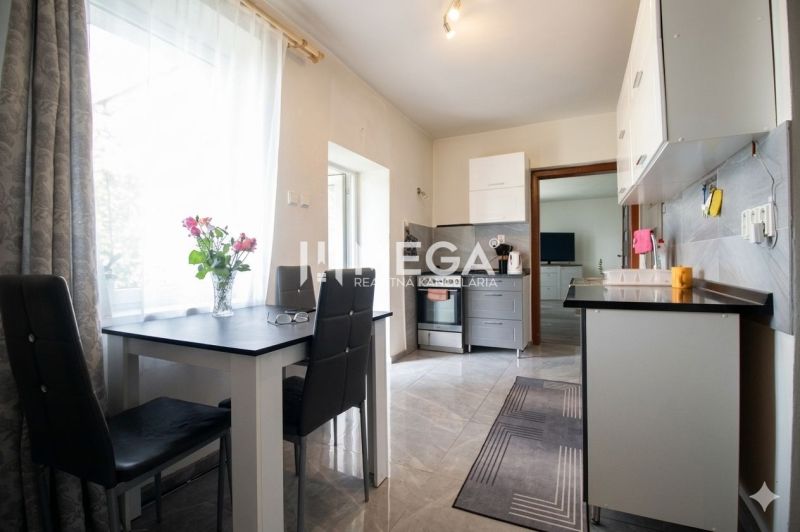 Küche in einem Einfamilienhaus mit Esstisch, Blumen und Geräten.
