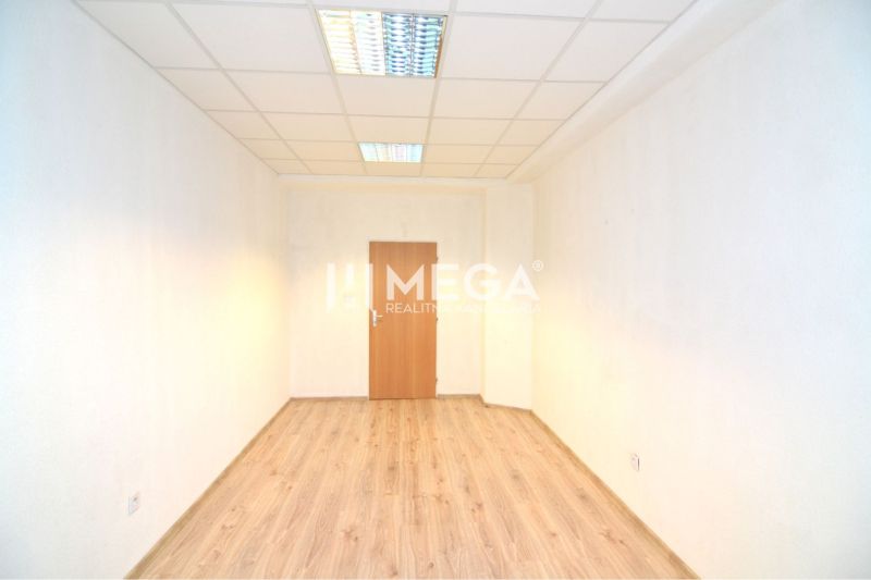 Ein Büro mit einem Boden in Holzoptik, weißen Wänden und Deckenbeleuchtung.