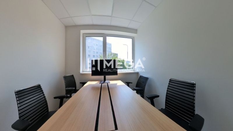 Büroinnenraum mit langem Tisch, vier Stühlen und einem Fenster.