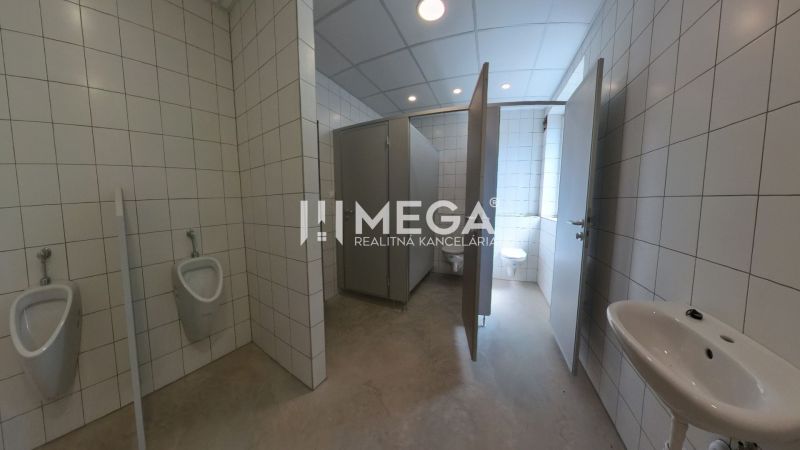 In den Büros befinden sich Toiletten mit weißen Fliesen und mehreren Kabinen.