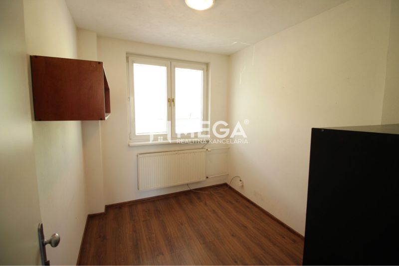 Ein Zimmer im Büro mit einem Boden in Holzoptik, weißen Wänden und einem Wandschrank.