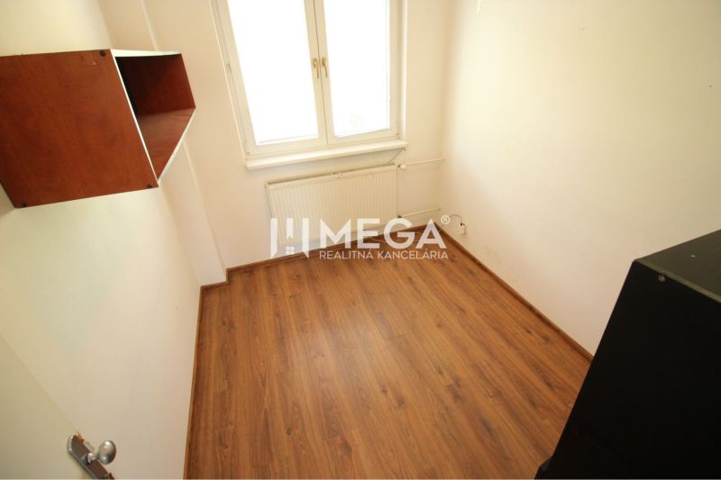 Kleines Büro mit Regal, Boden mit Holzdekor, Fenster und Heizkörper.