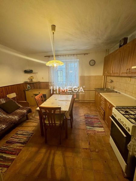 Küche in einem Einfamilienhaus mit Holzdekor auf den Stühlen und einem großen Tisch.