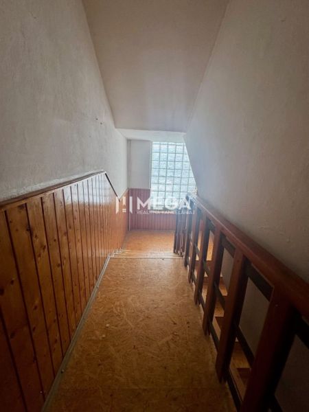 Flur mit Holzverkleidung und Geländer, Boden mit Holzdekor, Fenster aus Glasbausteinen.
