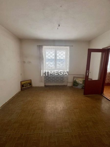 Ein Zimmer in einem Einfamilienhaus mit einem Holzboden und an die Wand gelehnten Bildern.