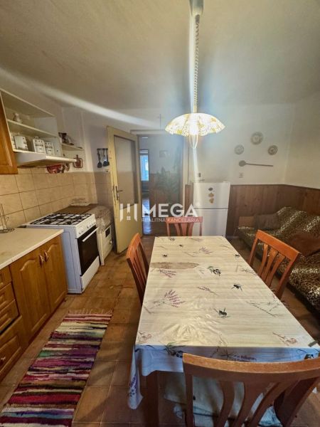 Küche in einem Einfamilienhaus mit Holzdekor, Esstisch, Herd und Kühlschrank.