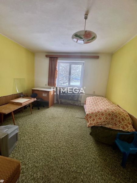 Ein Zimmer in einem Einfamilienhaus mit einem Bett, einem Schreibtisch und einem grünen Teppich.