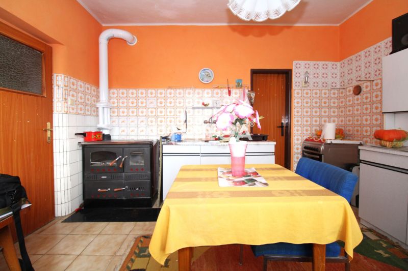 Küche in einem Einfamilienhaus mit orangefarbenen Wänden, Fliesen und Esstisch.