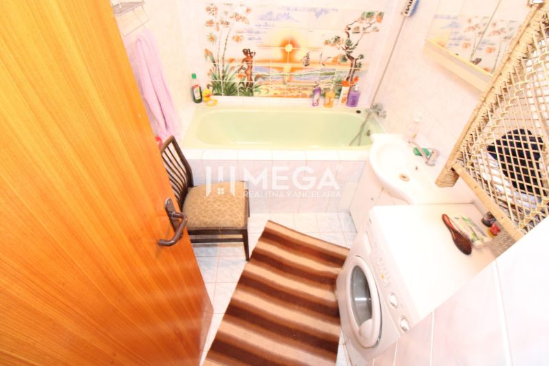 Badezimmer in einem Einfamilienhaus mit grüner Badewanne, Waschmaschine und dekorativen Fliesen.