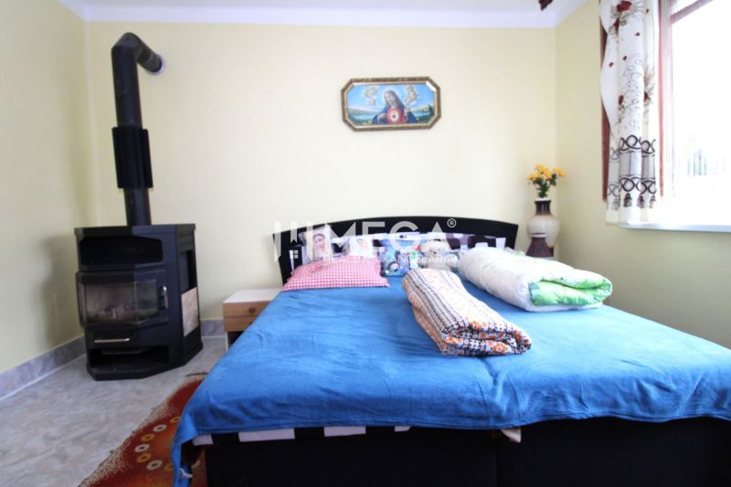 Interieur eines Einfamilienhauses mit Bett, Kachelofen und bunten Accessoires.