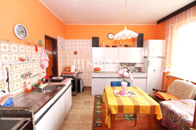 Küche in einem Einfamilienhaus mit farbiger Wand, Fliesenverkleidung und Esstisch.