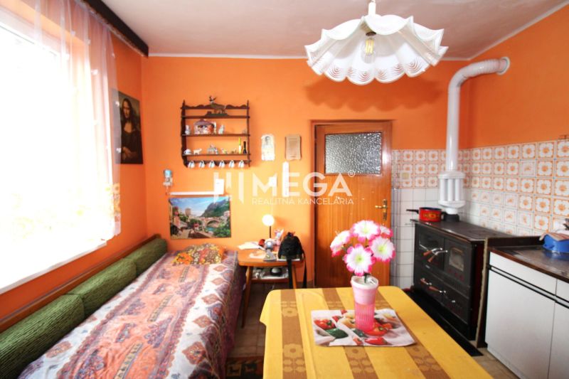 Eine Küche in einem Einfamilienhaus mit orangefarbenen Wänden, einem Herd und Blumendekoration auf dem Tisch.