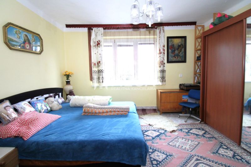 Ein Schlafzimmer in einem Einfamilienhaus mit einem blauen Bett, Holzmöbeln und einem bunten Teppich.