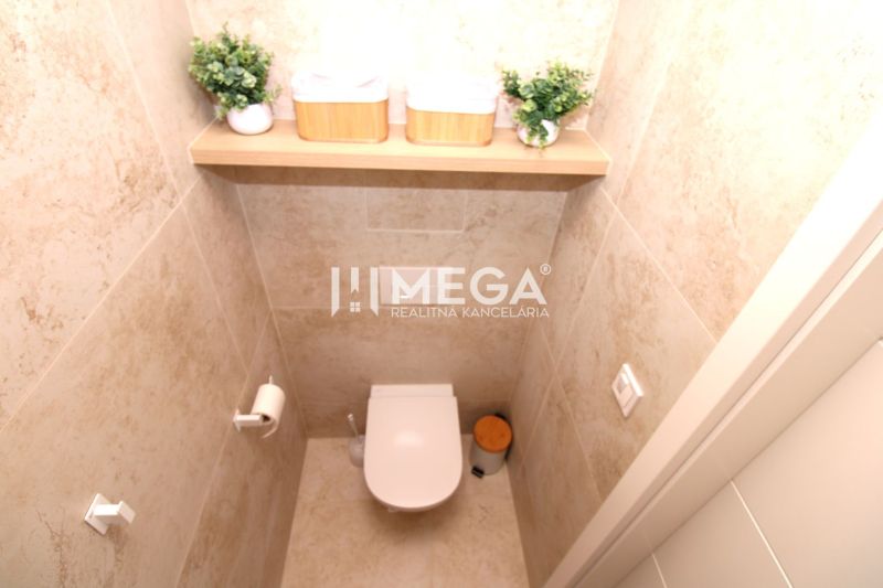 Eine Toilette mit Marmorverkleidung und dekorativen Pflanzen in einer 3-Zimmer-Wohnung.