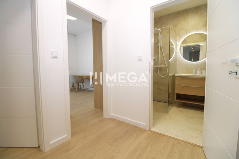 Flur in einer 3-Zimmer-Wohnung mit sichtbarem Badezimmer und Boden in Holzoptik.
