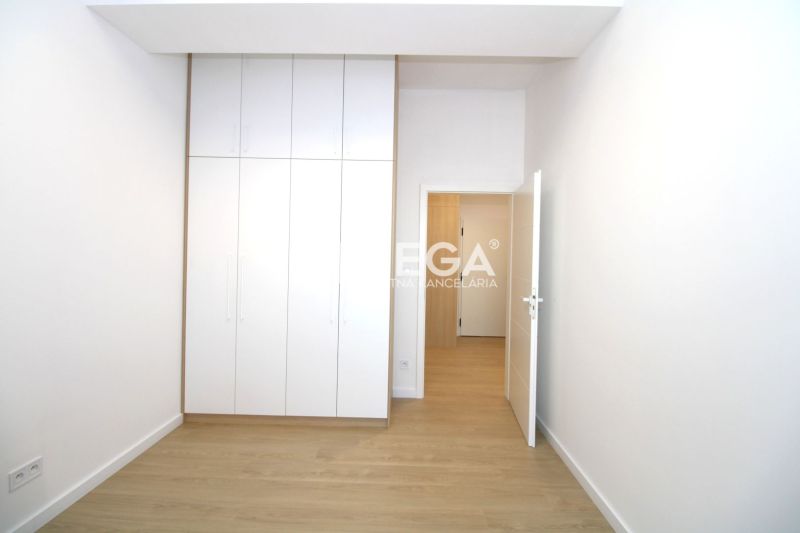 Ein Zimmer in einer 3-Zimmer-Wohnung mit einem weißen Einbauschrank und einem Boden in Holzoptik.